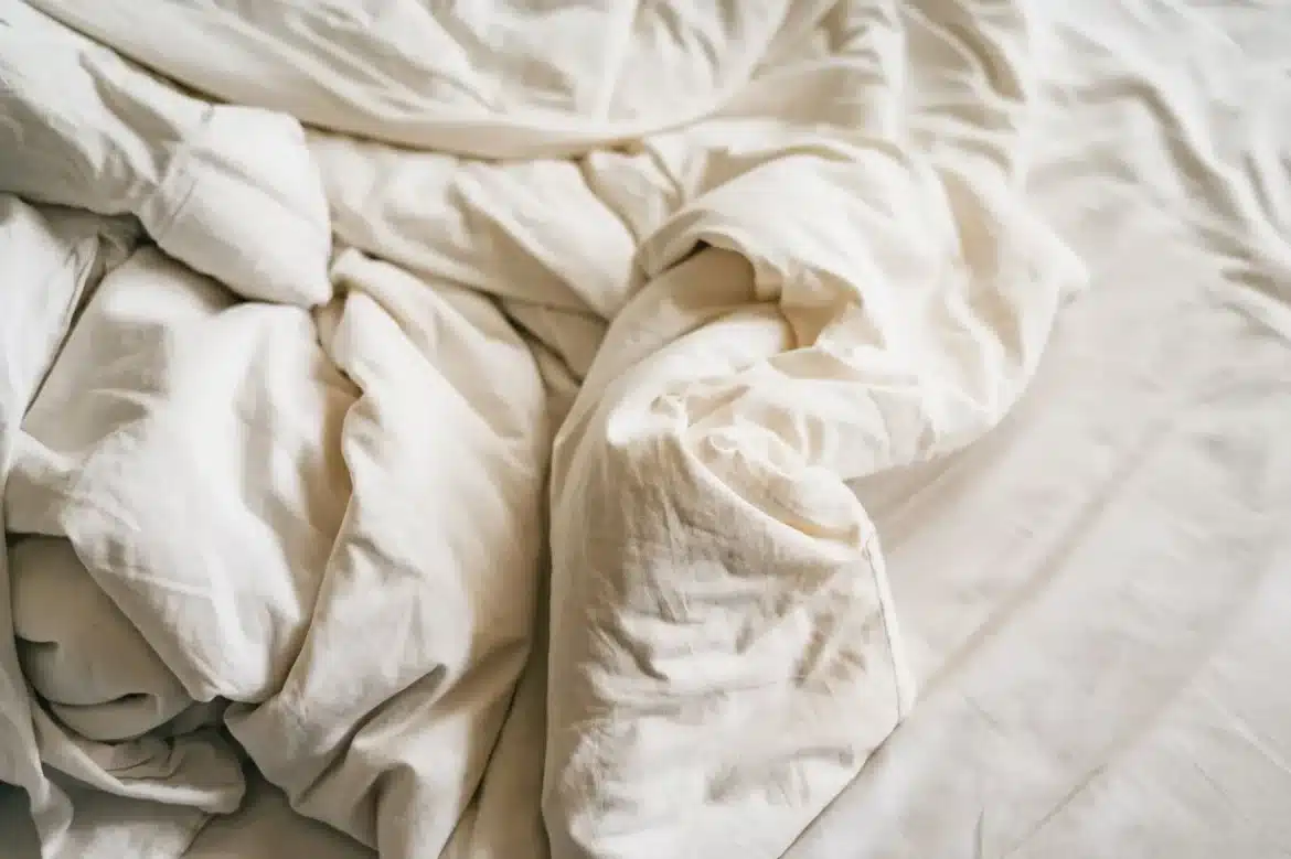 Personne se réveillant la nuit, draps humides de sueur, lumière tamisée