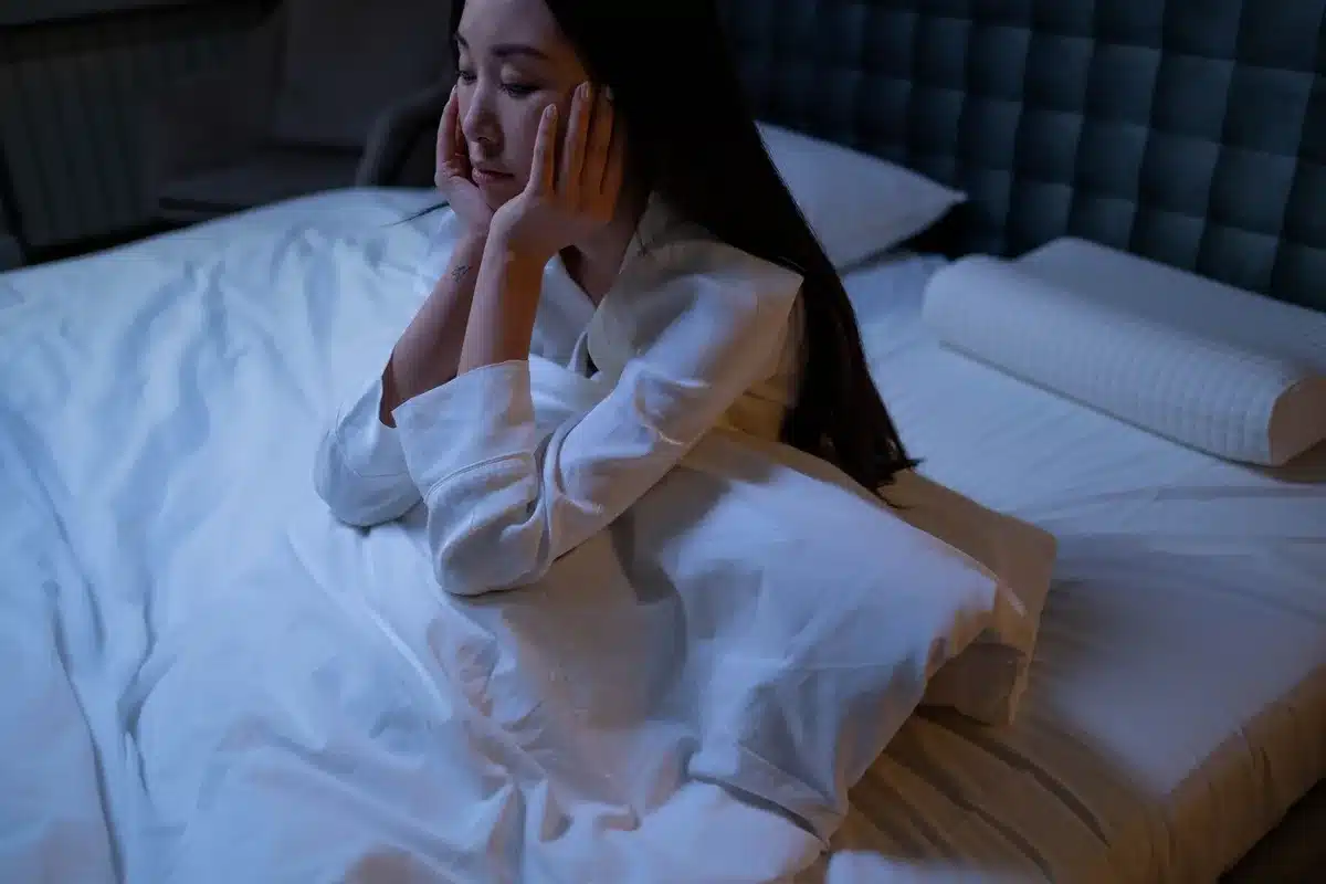 Une personne stressée, éveillée la nuit, illustrant les facteurs qui perturbent le sommeil.