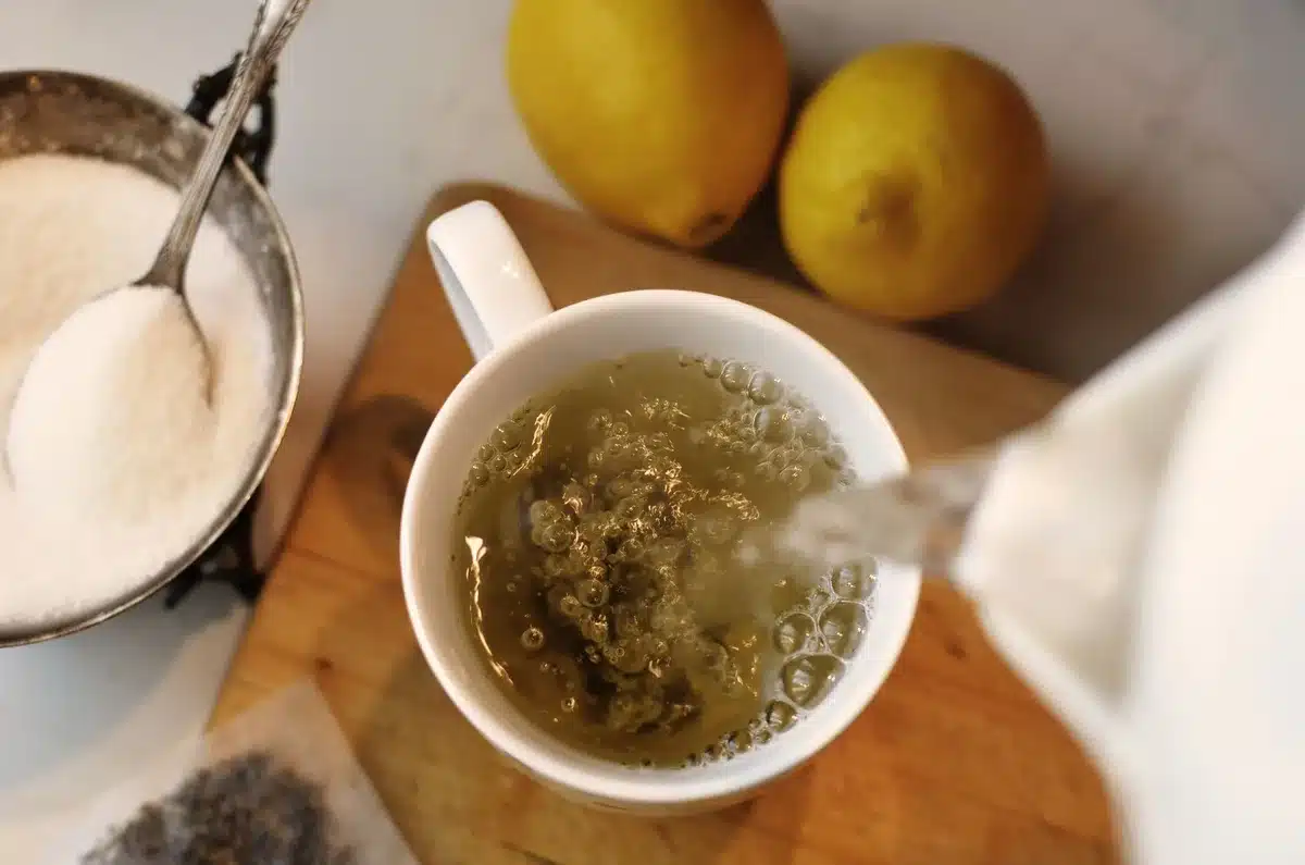 Infusion de romarin en préparation : eau chaude versée sur des feuilles de romarin frais dans une tasse.