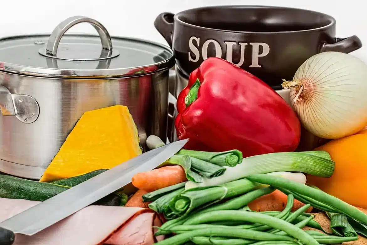 Table de cuisine en journée avec œufs, légumes et mains préparant une omelette